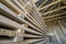 Perspective view of neatly piled long stack of natural uneven rough wooden boards inside attic room under construction. Industrial