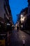 Perspective view over tiny cozy French street with pedestrians walking at dusk