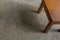 Perspective view of small teak table on beige carpet.
