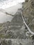 Perspective view of stone block staircase with nautical rope railing on rock wall and direct access to the seashore. Amazing view