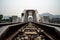 Perspective view of white railroad bridge with mountains and blue sky background.