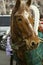 Perspiring red horse with white spots covered with a green raincoat in a harness is resting after a trip with children on the squa