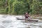 Peruvian boy paddles in a boat built from a log on the tributary of the Amazon River, Pevas, Peru