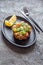 PERUVIAN NIKKEI FOOD. Salmon avocado ceviche on black plate, black background top view