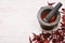 Pestle with mortar, surrounded by dried chili and habanero peppers