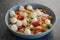 Pesto fusilli with mozzarella balls and tomatoes in blue bowl