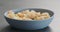 Pesto fusilli pasta with shrimps in blue bowl on concrete background