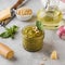 Pesto sauce in a jar with a piece of parmesan cheese, basil leaves, pine nuts and olive oil in a bottle. Italian cuisine