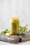 Pesto sauce in a jar with a piece of parmesan cheese, basil leaves, pine nuts on a wooden board. Italian cuisine