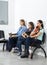 Pet Owners Sitting On Chairs In Waiting Area