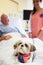 Pet Therapy Dog Visiting Senior Male Patient In Hospital