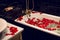 Petals of red roses in a white bathroom with black tiles