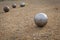 Petanque balls on a sandy pitch with other metal ball in the background