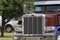 A peterbilt Semi in a parade with green tree`s and a chrome grill closeup