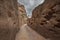 Petra Jordan, Narrow tunnel with a path carved into red rocks in the dry mountain