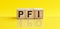 Pfi word is made of wooden building blocks lying on the yellow table