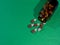 Pharmaceutical capsules and glass bottle on green background.