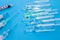 Pharmaceutical glass vials or ampules with liquid drug inside lie near syringes with needles on blue uniform background. Concept p