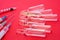 Pharmaceutical glass vials or ampules with liquid drug inside lie near syringes with needles on red uniform background. Concept pr