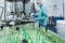 Pharmaceutical industry man worker in protective clothing operating production of tablets in sterile working conditions