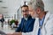 Pharmaceutical sales representative presenting new medication to doctor in medical building, holding box with medication