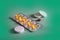 Pharmaceuticals pills medicine honey color capsules and white pills on green background