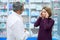 Pharmacist consulting woman with headache in drugstore.