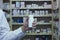 Pharmacist holding white vitamin bottle in front of dispensary shelves