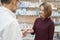 Pharmacist offering blister pack of pills to customer.