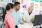 Pharmacist Showing Products To Couple At Checkout Counter