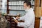 Pharmacist in vintage old pharmacy. Senior man chemist working with a tablet-pc in the pharmacy while reading