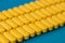 Pharmacology industry produce concept of many rows of yellow pills tablets of vitamin drugs on blue surface