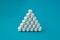 pharmacology medical concept pyramid of white pills tablets drugs on cyan surface with copyspace