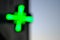 Pharmacy green cross blurred over light and dark background