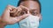 Pharmacy and medication. Close up of black doctor in protective mask holding medical pill in hand, blue background