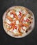 Philadelphia pizza with salmon, shrimps, tomatoes, mozzarella, capers, Philadelphia cheese. Neapolitan round pizza on dark