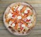 Philadelphia pizza with salmon, shrimps, tomatoes, mozzarella, capers, Philadelphia cheese. Neapolitan round pizza on wood