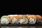 Philadelphia sushi roll with king prawn, smoked eel, salmon and cream cheese on a black background. Traditional Japanese