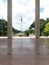 Philippine flagpole on a park viewed with two cream colored columns with maroon tiled floor