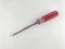 A Phillips-shaped screwdriver with a red plastic handle placed on a white surface.