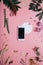 phone with a clear screen and white circle shape in flowers on pink background. Flat lay. Top view