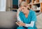 Phone, healthcare and worry with a woman nurse reading a text message while sitting on a sofa in a hospital office