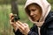 Phone lenses for macro photography. A woman holds a mobile phone with a macro attachment in her hands and takes pictures of plants