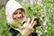 Phone lenses for macro photography. A woman holds a mobile phone with a macro attachment in her hands and takes pictures of plants