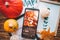 Phone and pictures in frame on brown wood background with pumpkins