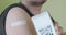 Phone with QR code displayed for scanning next to vaccinated arm with medical plaster. Concept of Coronavirus digital certificate