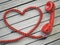 Phone reciever and cord as heart on white wooden background. Love hotline concept. 3d