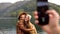 On the phone shoot two attractive girls young women fashionably dressed on vacation on a lake in the mountains. lesbian