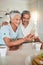 Phone, video call and elderly couple in a kitchen happy, smile and embrace in their home. Smartphone, love and old