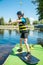 Photo of a 10-year-old boy standing on a wakeboard on land and preparing for sports. He wears a helmet. Safety precautions for